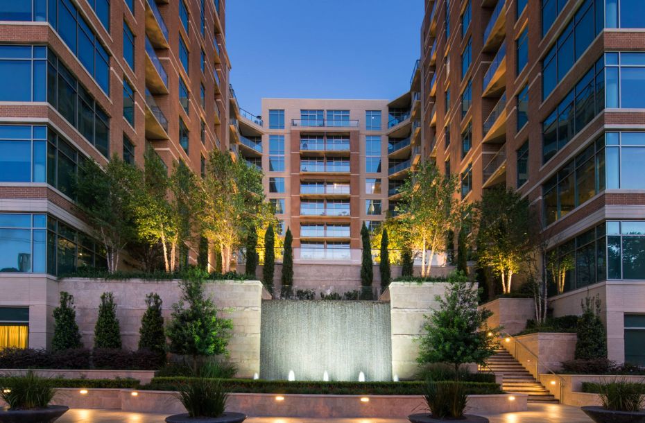 Hanover Company, Hanover Southampton Modern building facade with a central illuminated water feature and surrounding greenery at dusk.