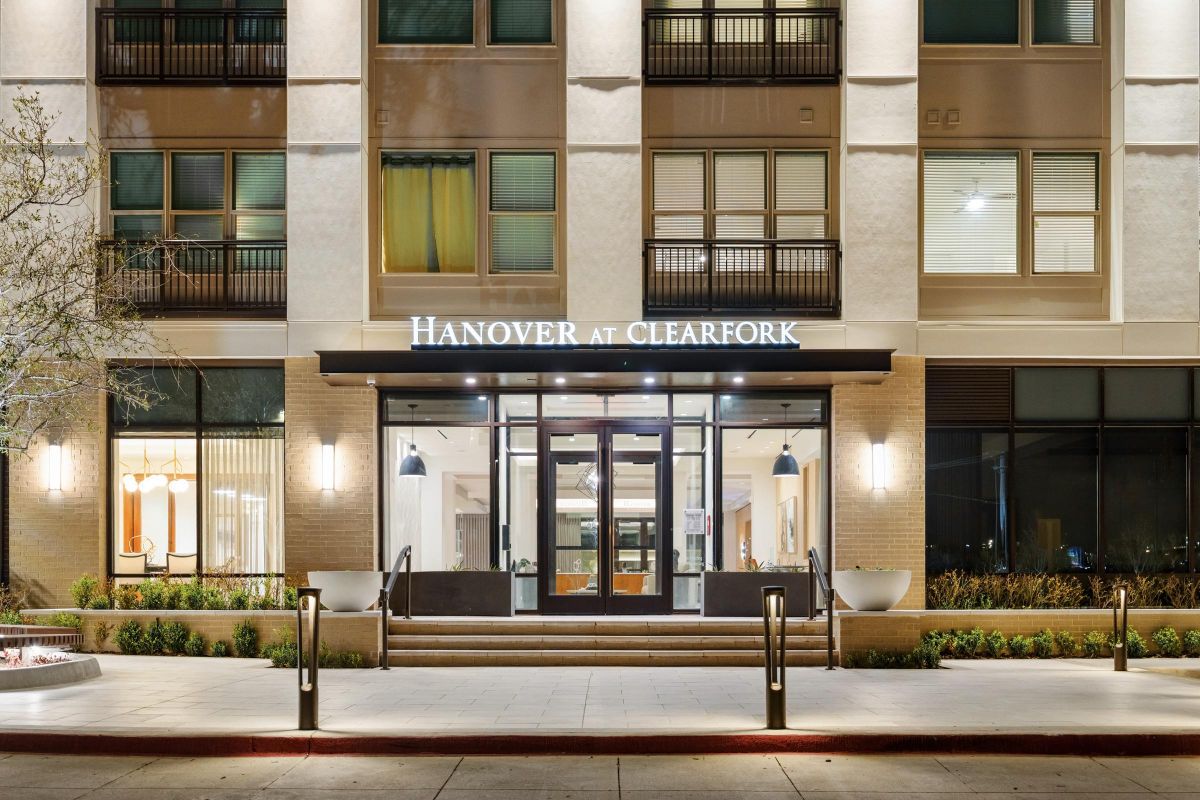 Entrance of a modern building labeled "Hanover at Clearfork" with large windows and sleek lighting.