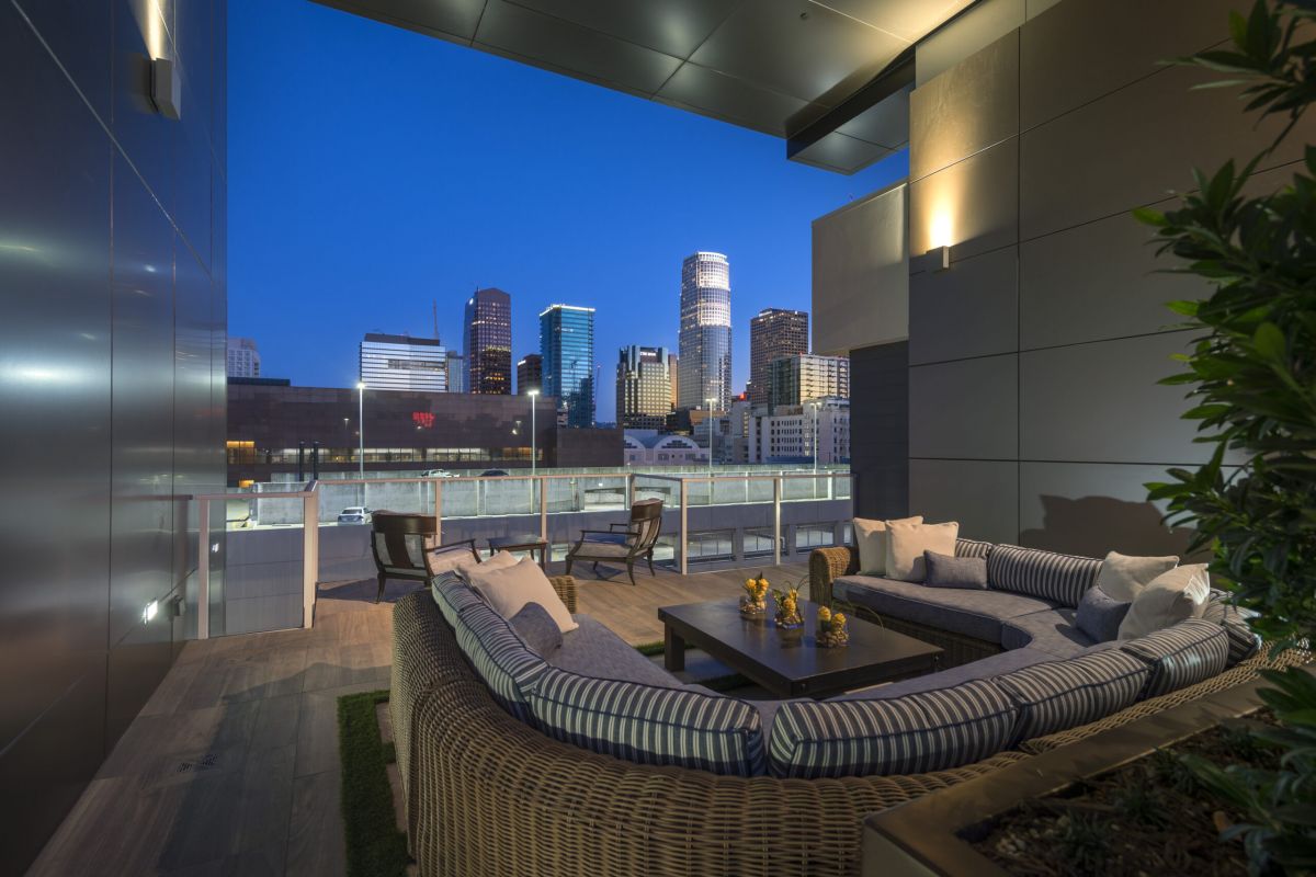 Modern rooftop patio with circular seating, table, and city skyline view at dusk.