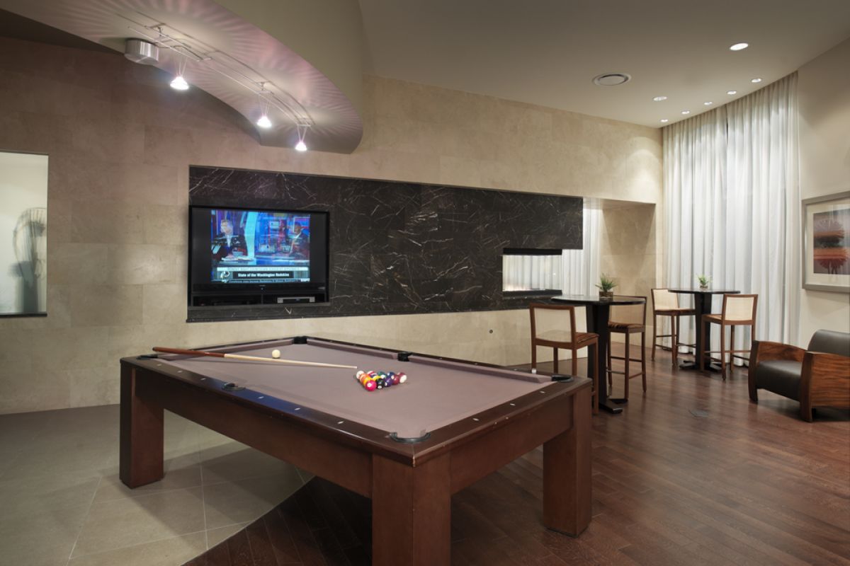 Modern game room with a pool table, TV on the wall, seating area, and contemporary decor.