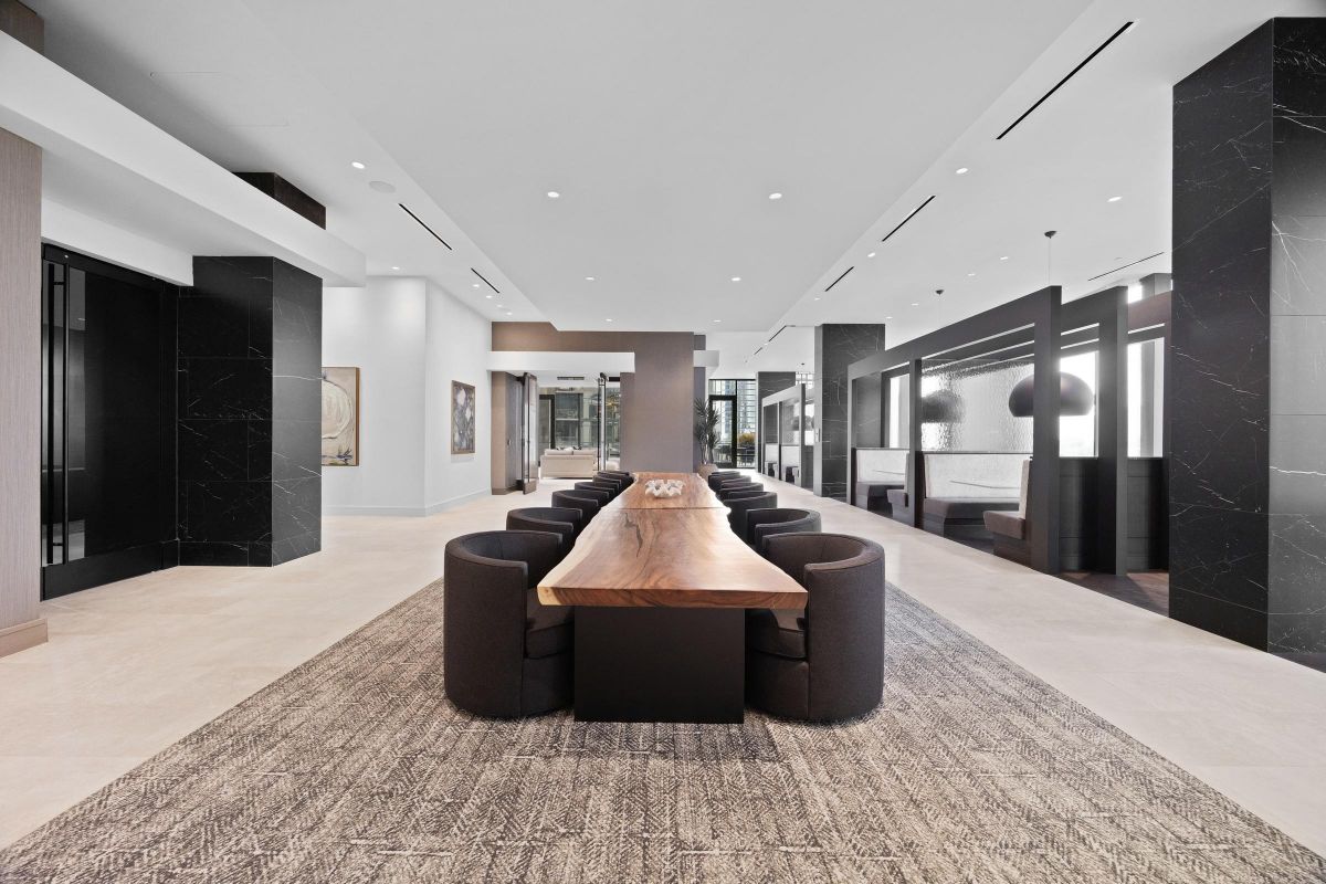 Modern dining area with long wooden table, round chairs, and elegant decor in a spacious, open interior.