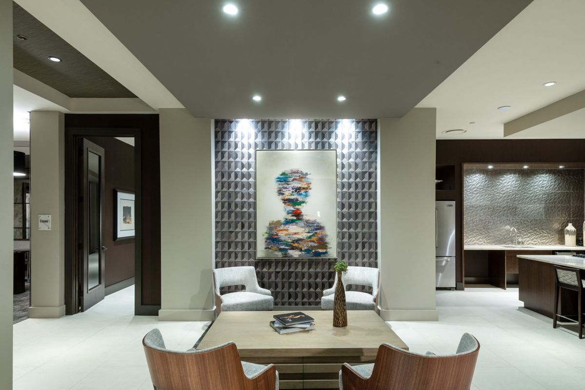 Modern lounge with two wooden chairs, a coffee table, and abstract art on a textured accent wall.