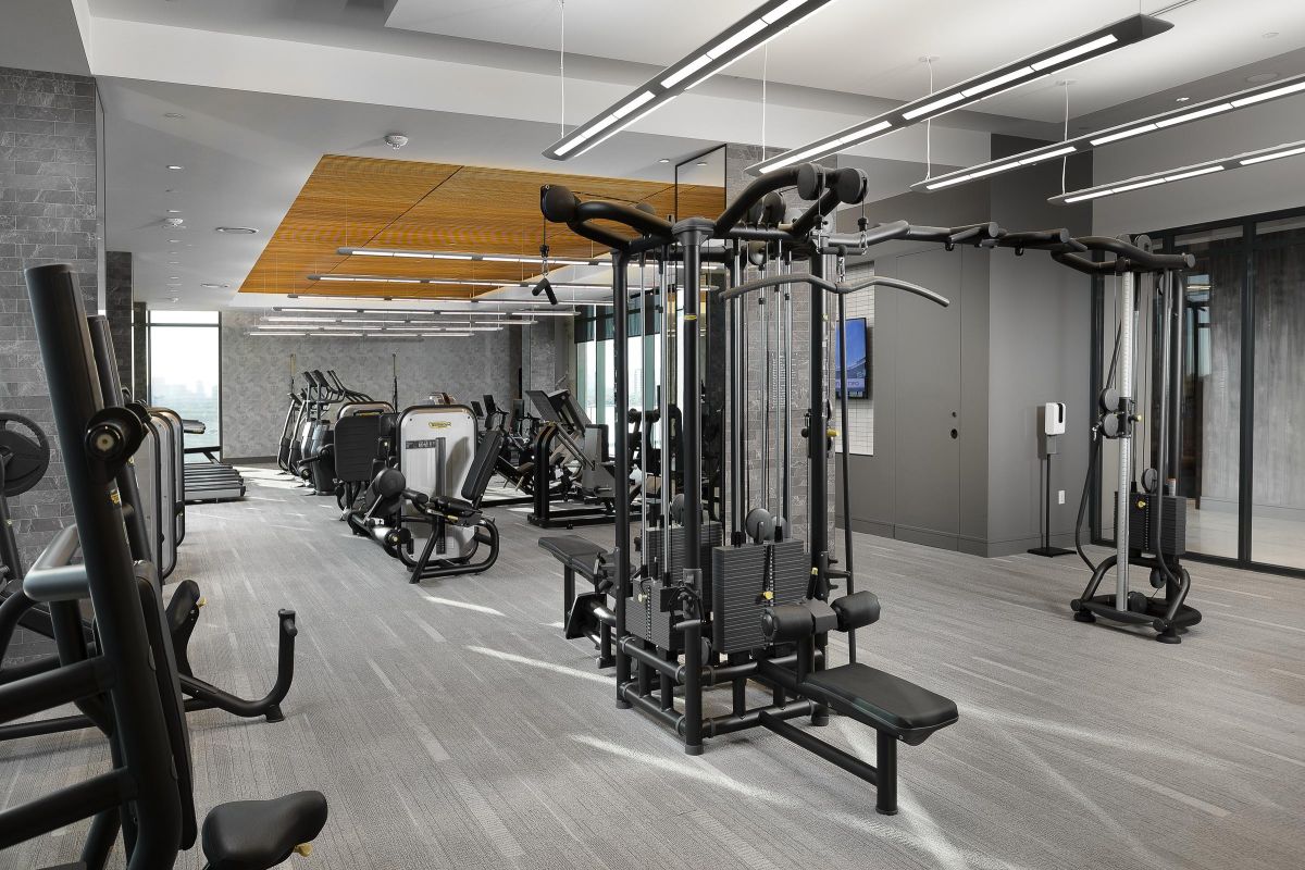 Modern gym with exercise equipment, including weight machines and treadmills, in a spacious, well-lit room.