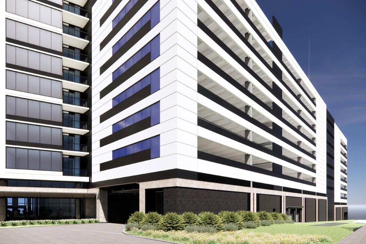 Modern multi-story building with striped black and white facade, surrounded by greenery and clear blue sky.