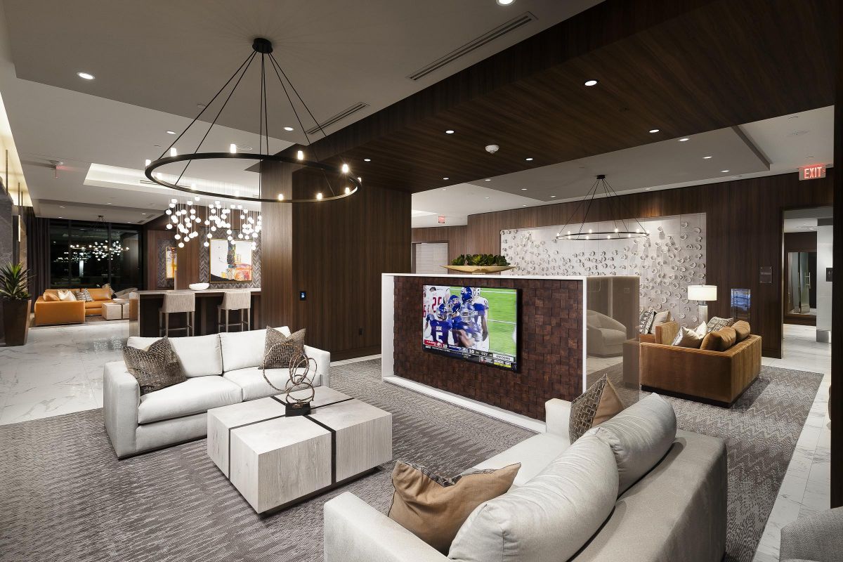 Modern lounge with cozy seating, a large TV, stylish lighting, and contemporary decor in a warmly lit room.