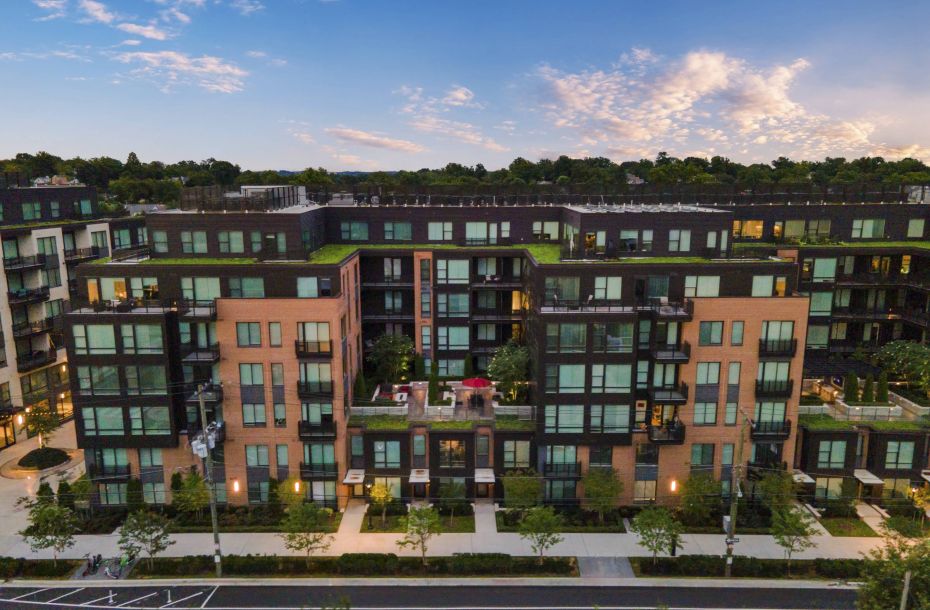 Hanover Company, Hanover 8th Street A modern apartment complex with trees and a road in front, set against a blue sky with clouds at dusk.