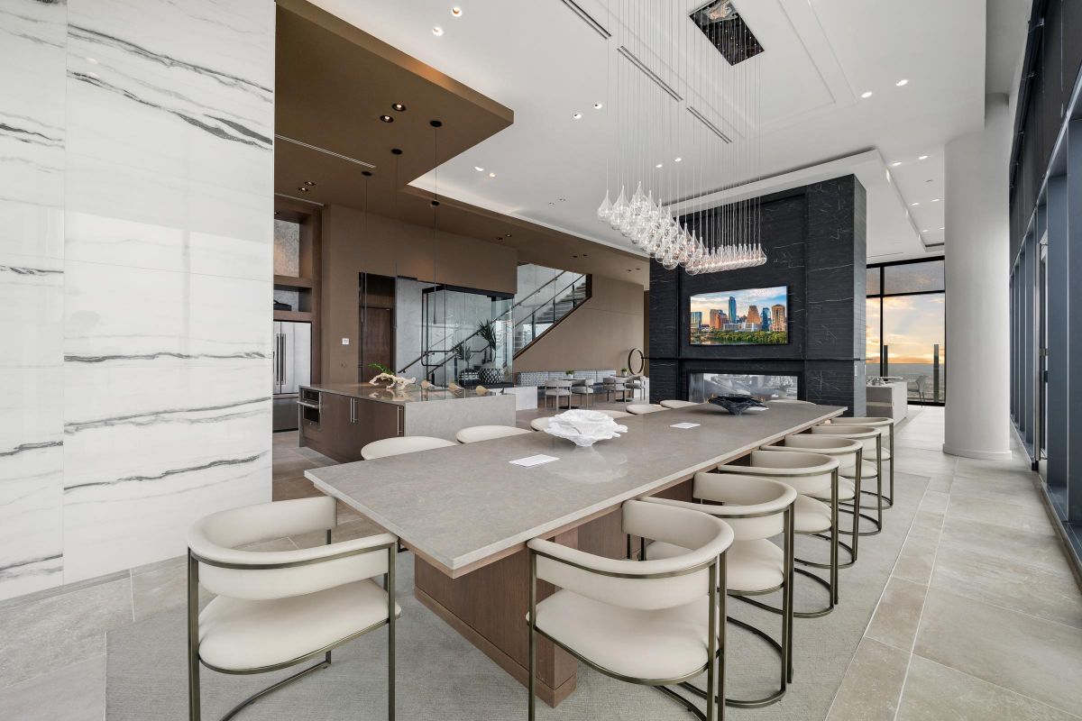 Modern open-concept kitchen with a long island, elegant bar stools, and large windows overlooking a city skyline.