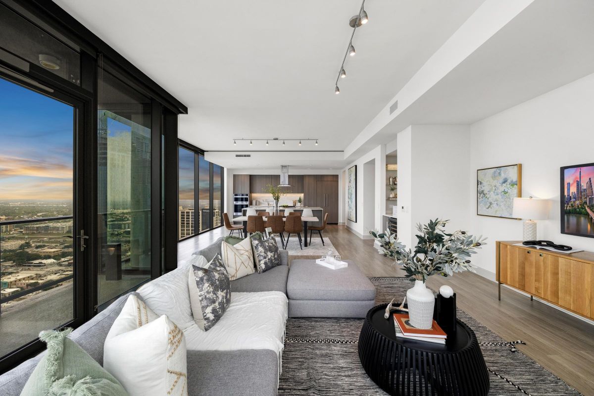 Modern living room with city view, sectional sofa, dining area, large windows, and contemporary decor.