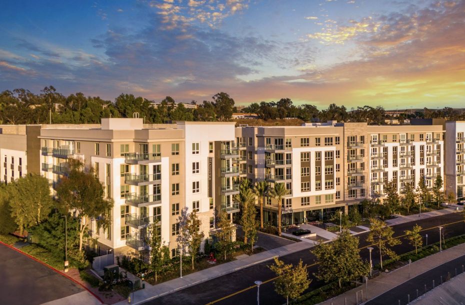 Hanover Company, Hanover Laguna Niguel Modern apartment complex with greenery, at sunset, under a cloudy sky.