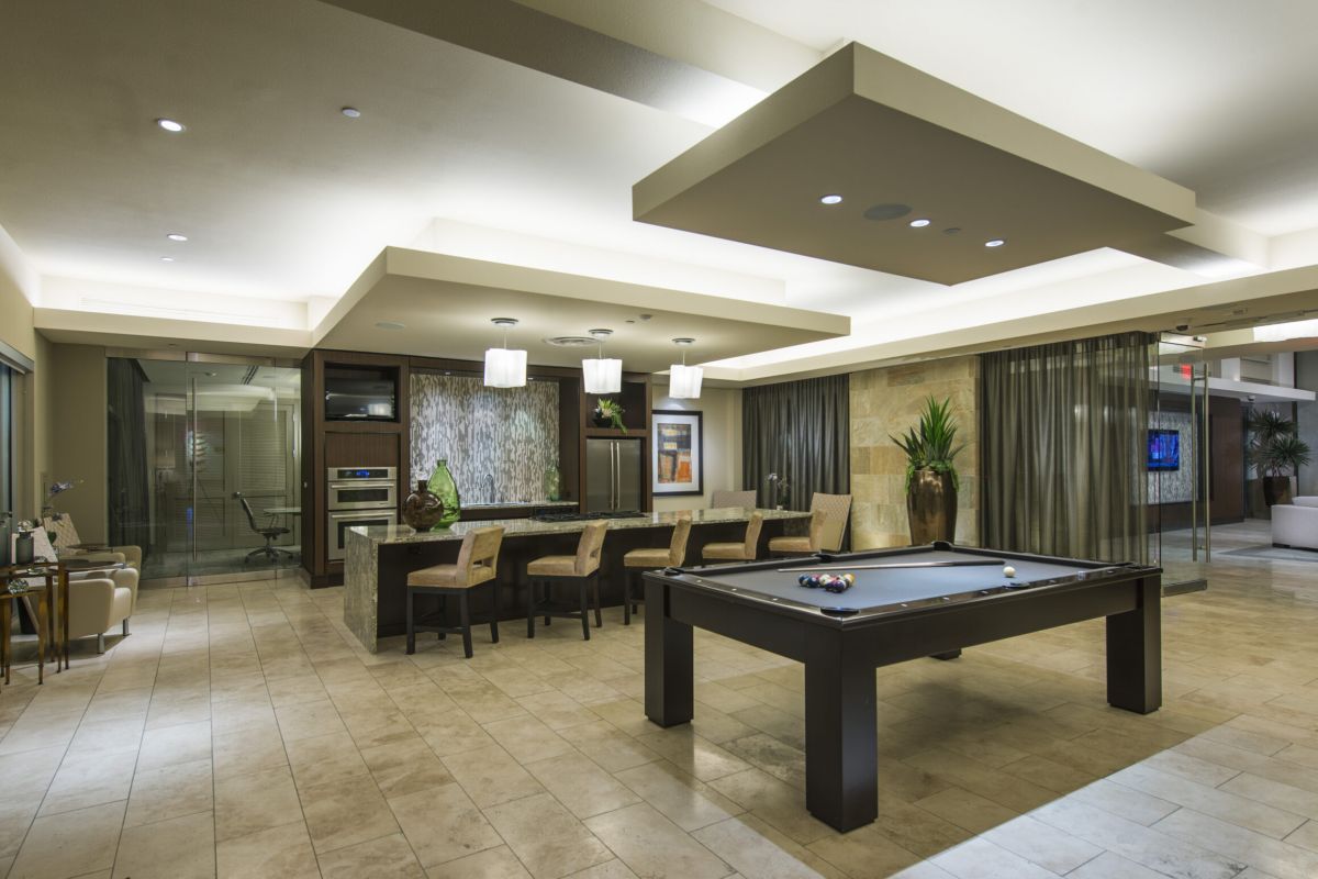 Modern lounge with a pool table, bar seating, and contemporary lighting in an open, spacious room.