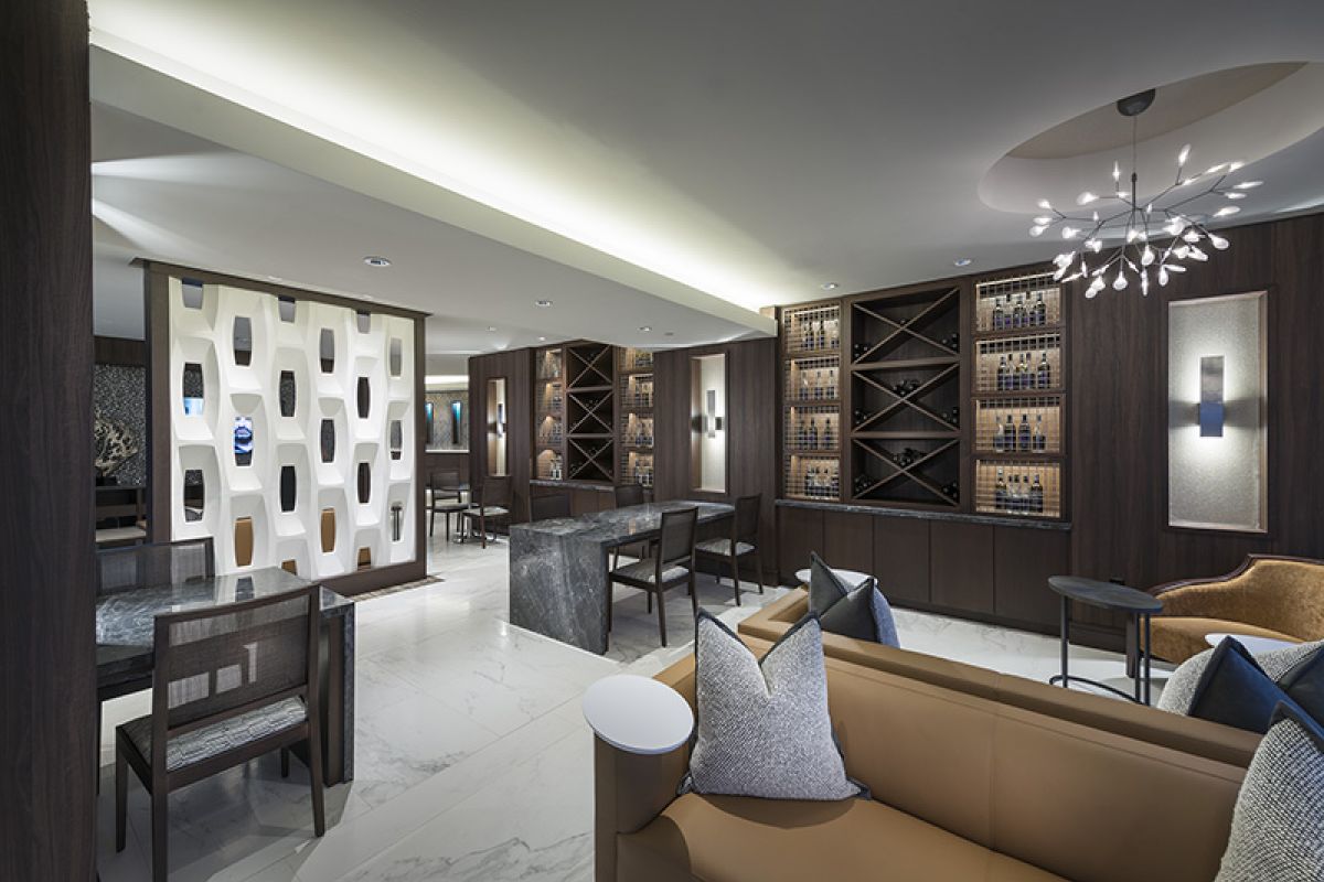 Modern hotel lounge with marble floors, stylish seating, wine racks, and contemporary lighting fixtures.