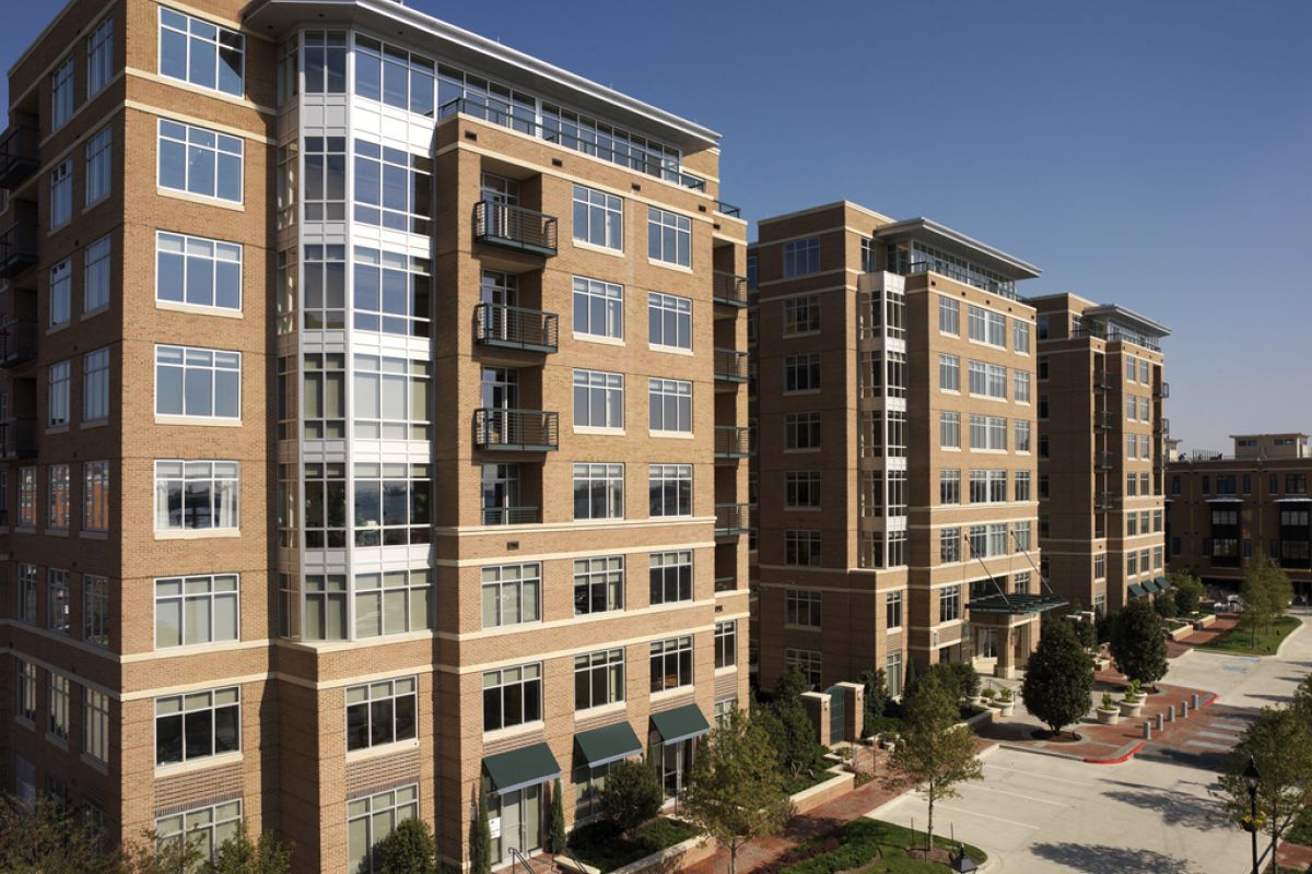 Modern mid-rise Baltimore apartments with large windows and balconies bask under a sunny sky.