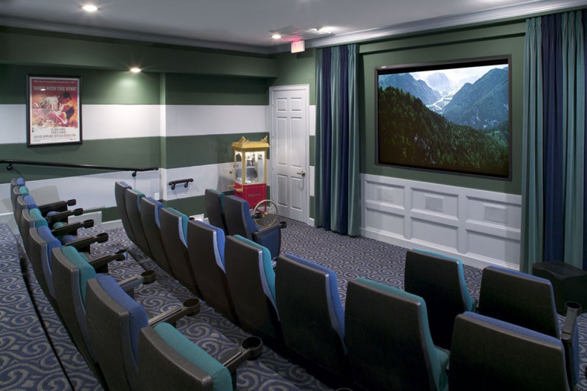Small home theater with rows of seats, popcorn machine, and a movie playing on a large screen.