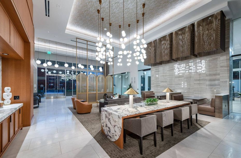 Hanover Company, Hanover Hollywood Luxury hotel lobby with modern décor, long marble table, pendant lights, and seating areas.