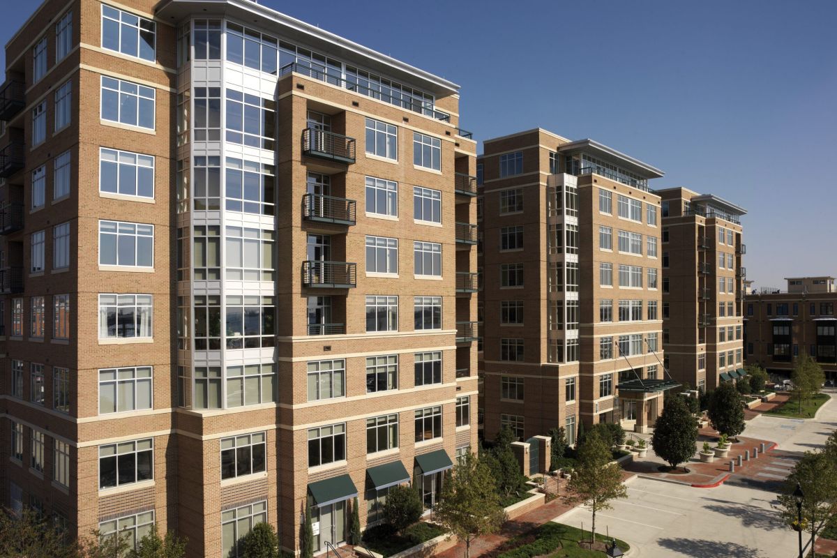 Modern mid-rise brick apartment buildings with large windows and balconies on a sunny day.