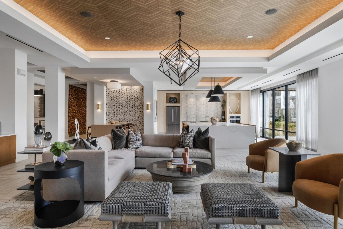Modern living room with a large gray sofa, geometric light fixture, and a mix of contemporary furniture.