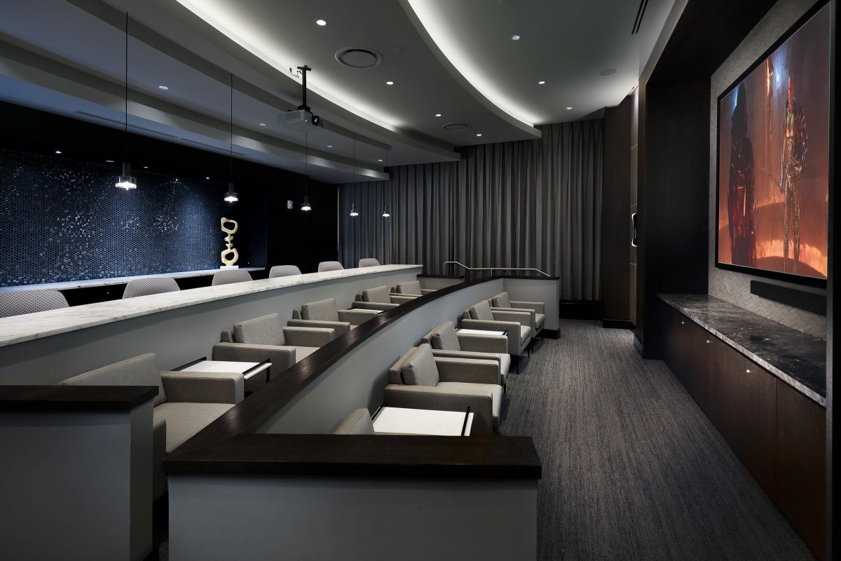 Modern conference room with tiered seating, curved ceiling, large screen, and soft lighting.