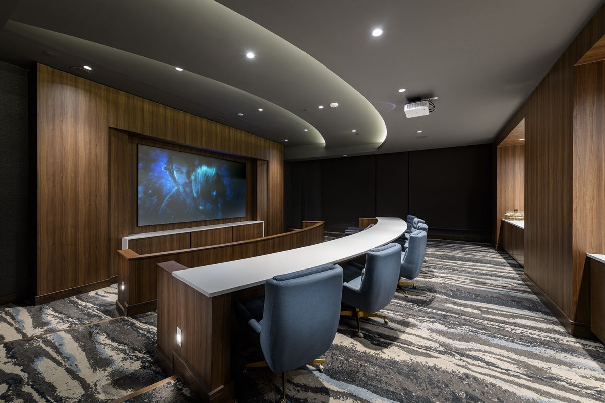 Modern home theater at Hanover Exton Square features curved desks, blue chairs, and a large screen—luxury apartment living redefined.