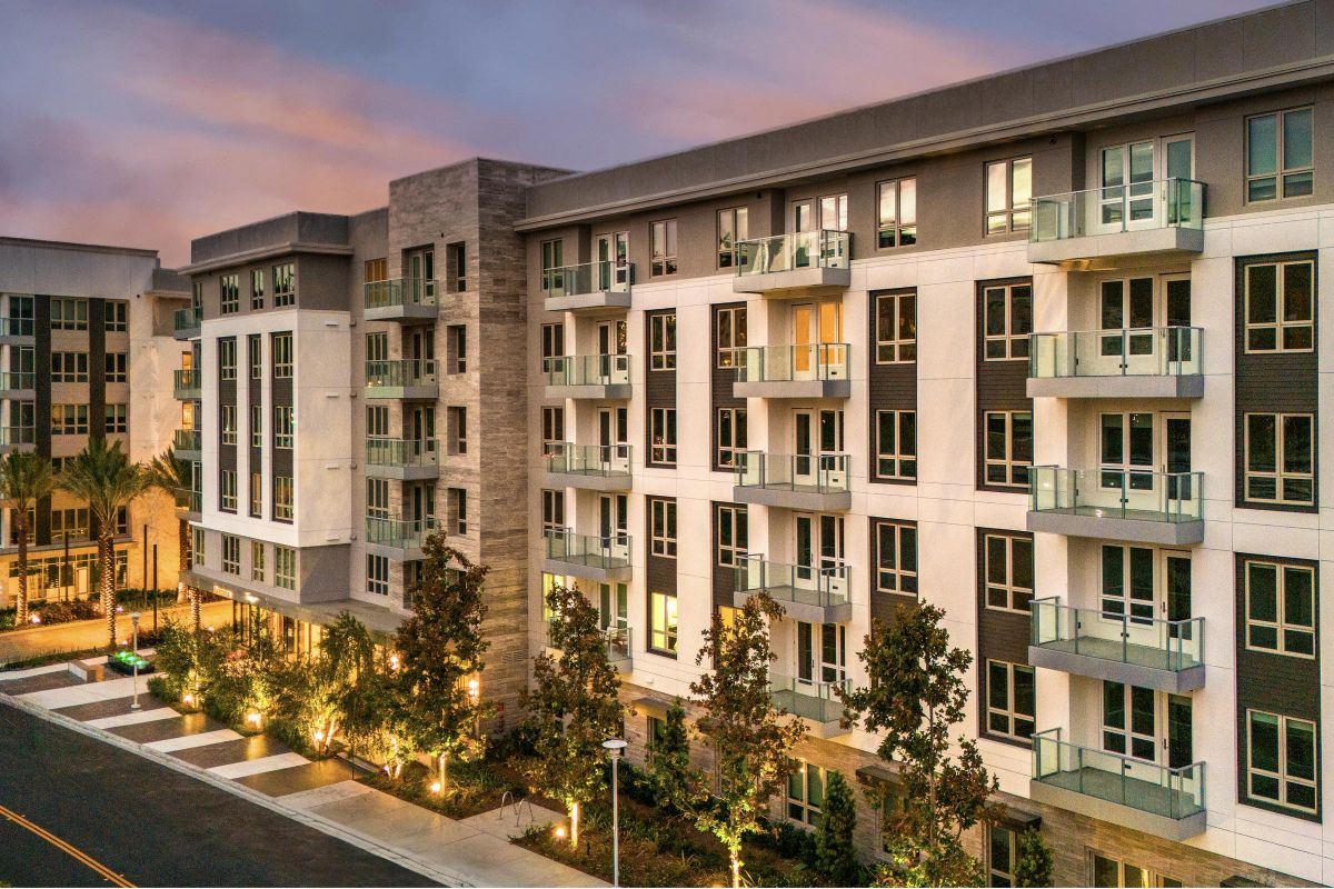 Hanover Laguna Niguel Modern apartment building at sunset, featuring multiple balconies and landscaped surroundings.