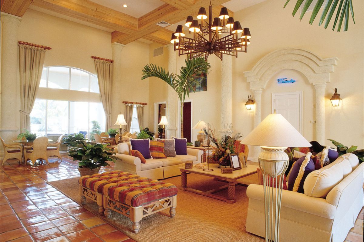 Spacious living room with high ceilings, cream sofas, large windows, and plants, inspired by Broadwater Galveston’s elegant style.