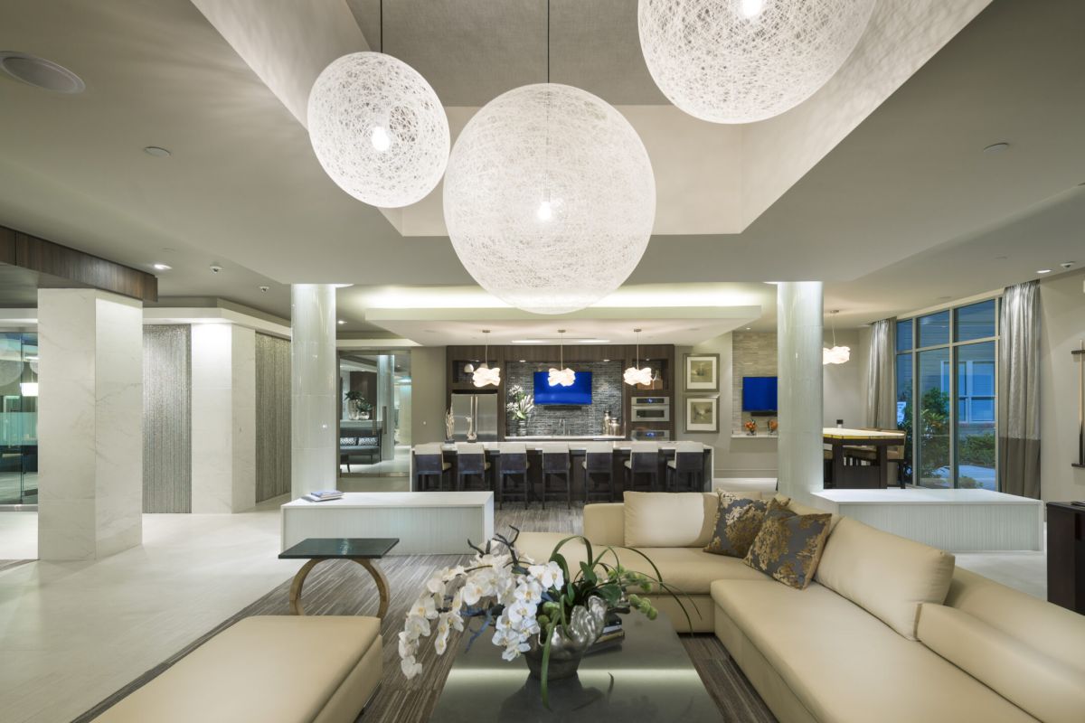 Modern, spacious living room and dining area with neutral tones, large sofa, and spherical pendant lights.