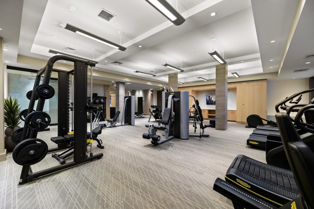 Modern gym with various exercise equipment including treadmills, weight machines, and a clean, well-lit interior.