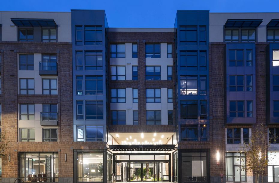 Hanover Company, Hanover Soma West Modern apartment building exterior with lit entrance at dusk.