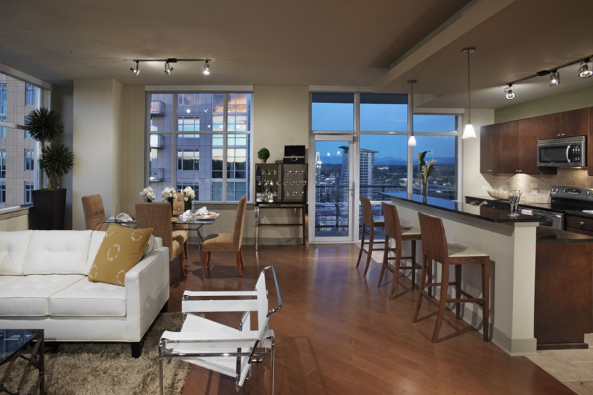 Modern open-plan apartment with large windows, city view, sleek kitchen, dining area, and stylish living room.