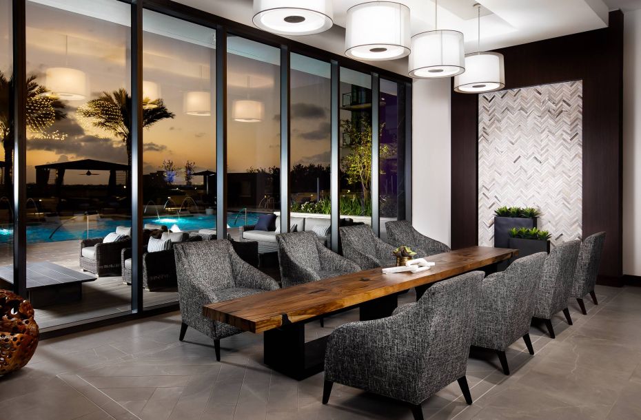 Hanover Company, The Driscoll at River Oaks Modern conference room with a long wooden table, gray chairs, and large windows showing a pool at sunset.