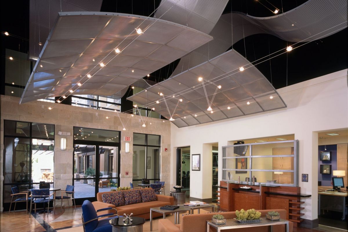 Modern office lobby with sleek furniture, polished floors, and wavy metal panels hanging from the ceiling.