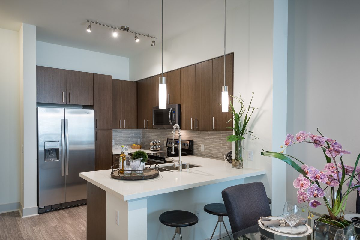 Modern kitchen with dark cabinets, stainless steel appliances, and a set dining table with pink flowers.