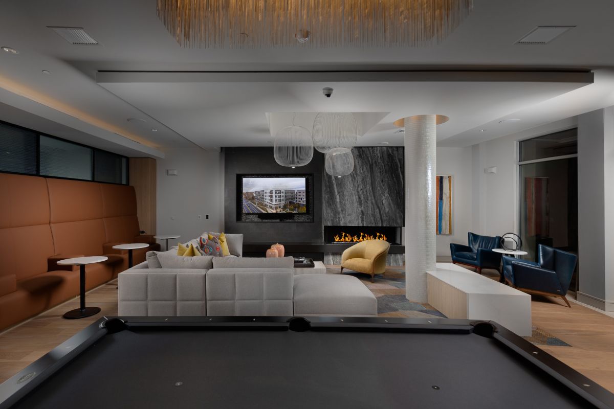 Modern lounge in Hanover with a pool table, sofa, fireplace, TV, and contemporary seating in a stylish interior.