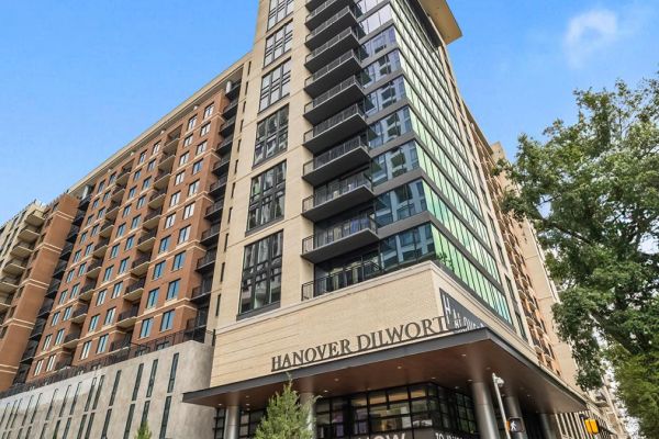 A modern high-rise apartment building with "Hanover Dilworth" and "Leasing Now" signs at the entrance.