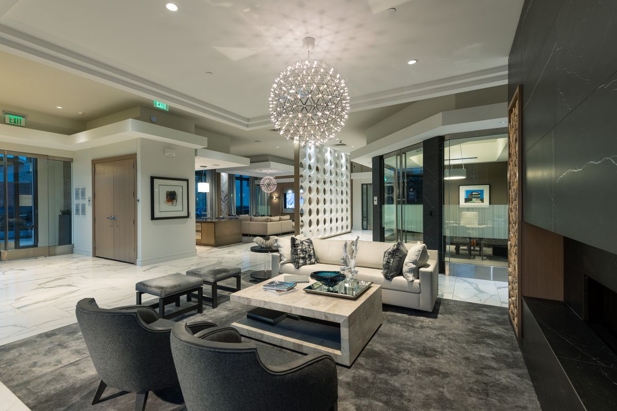 Modern lobby with elegant seating, marble floors, a statement chandelier, and contemporary decor.