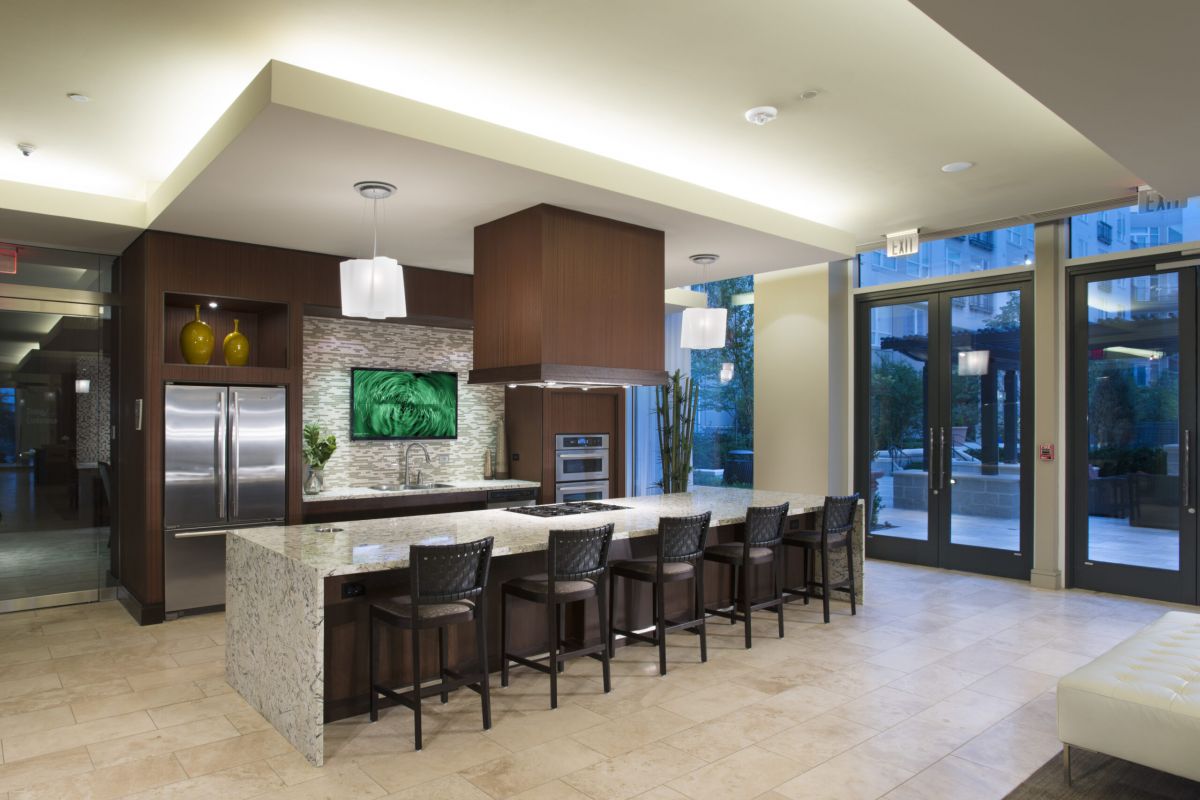 Modern kitchen with island seating, stainless steel appliances, and large windows letting in natural light.