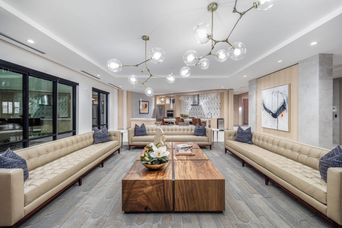 Modern Hanover lounge with beige sofas, wooden coffee tables, abstract art, and a contemporary chandelier.