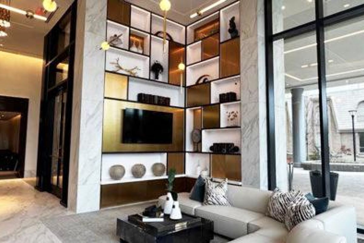 Modern lobby with a white sofa, decorative shelves, large windows, and natural light streaming inside.