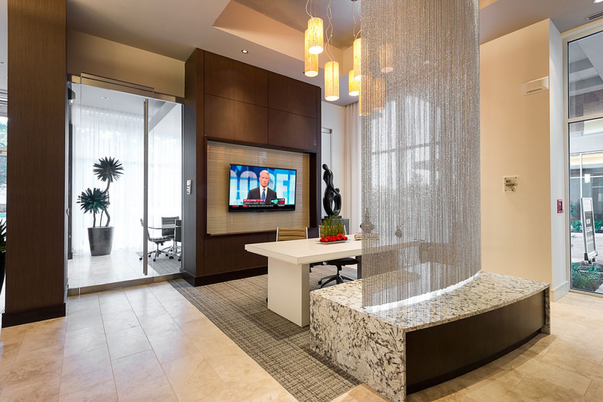 Modern office with a white desk, TV on the wall, hanging lights, and decorative divider with chain curtains.