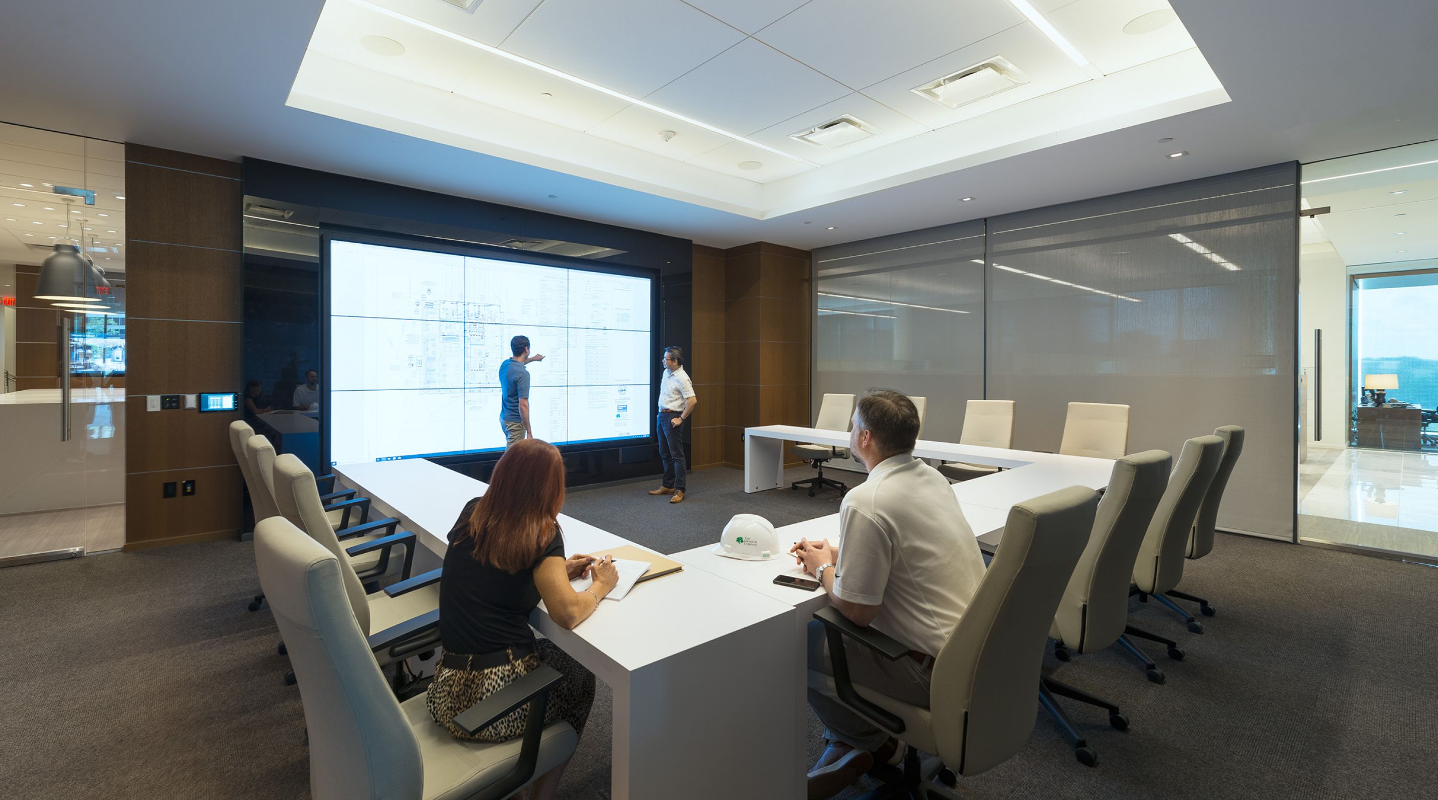 Four Hanover Company corporate employees in a modern conference room, analyzing a large screen with diagrams.