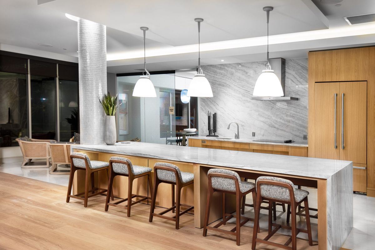 Modern kitchen at Hanover Mystic River with wooden cabinets, marble island, pendant lights, and open seating area.