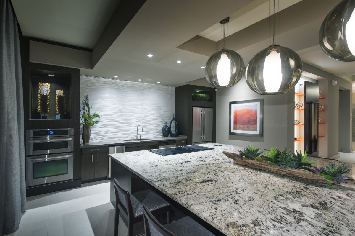 Modern kitchen with granite island, pendant lights, built-in appliances, and contemporary decor.