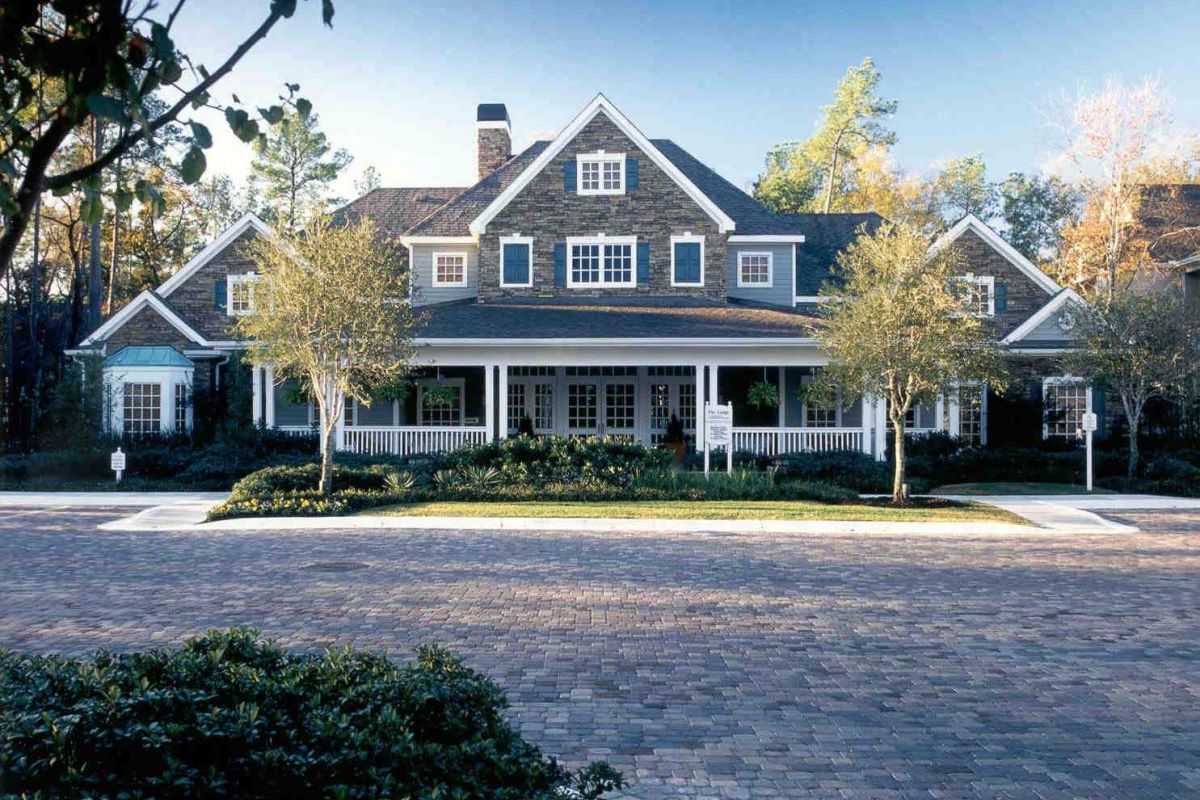 Large two-story house with dormer windows, white trim, and a wide front porch, like the homes near Churchill on the Park apartments in Dallas.
