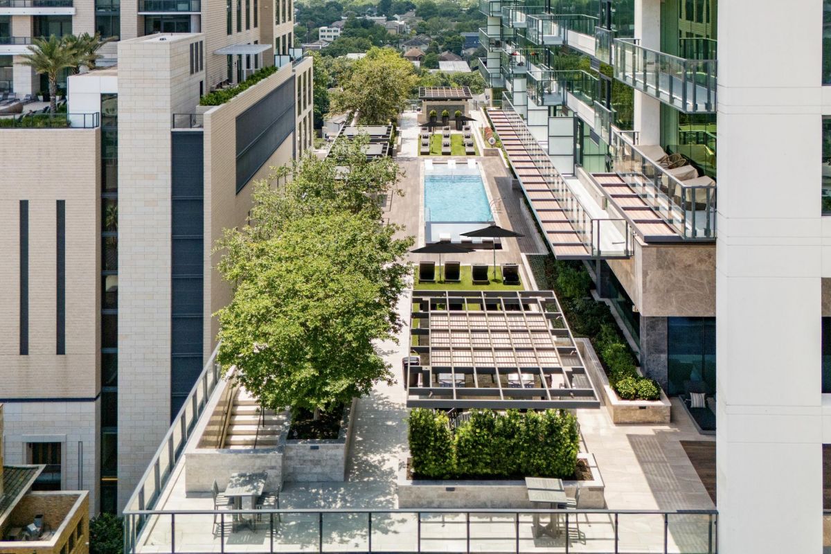 Aerial view of a modern apartment complex with a pool, trees, and seating areas.