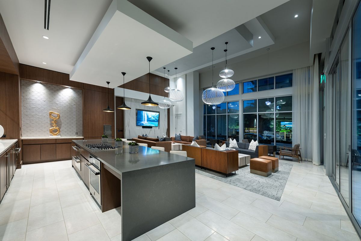 Modern open-concept kitchen and living area at Hanover Warner Center, with stylish lighting, large windows, and sleek furnishings.