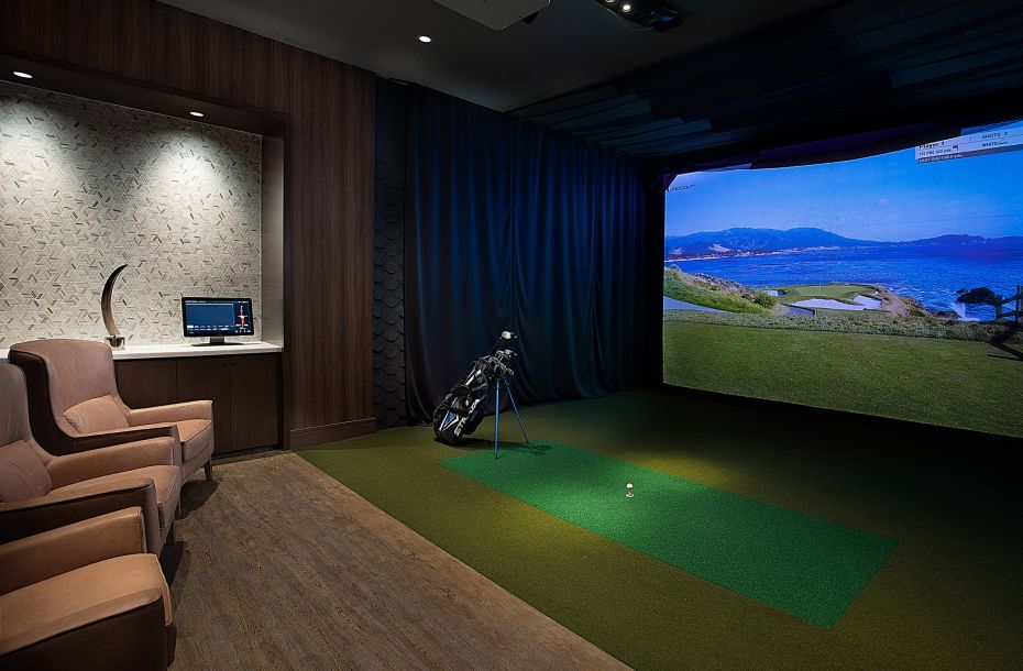 Hanover Company, Hanover River Oaks Indoor golf simulator room with virtual golf course display, two chairs, a computer, and golf equipment.