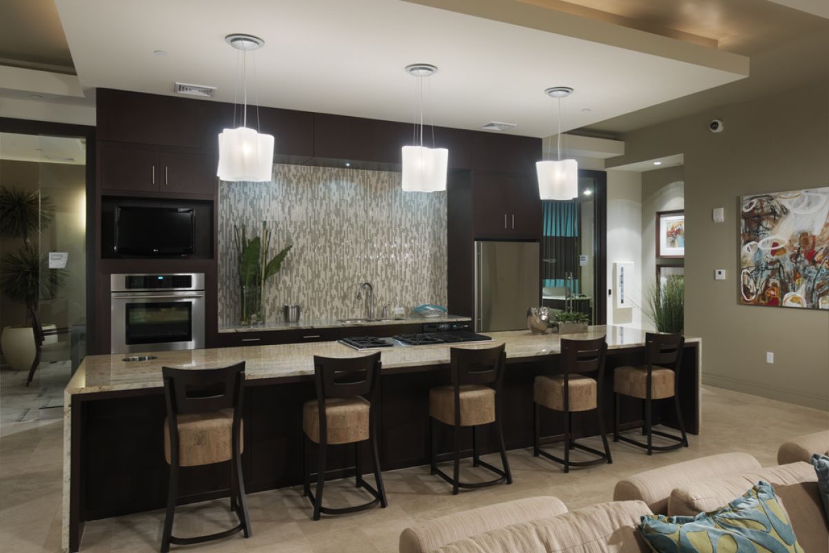 Modern kitchen at Charles River Landing features dark cabinets, a long island with barstools, and pendant lights above the counter.