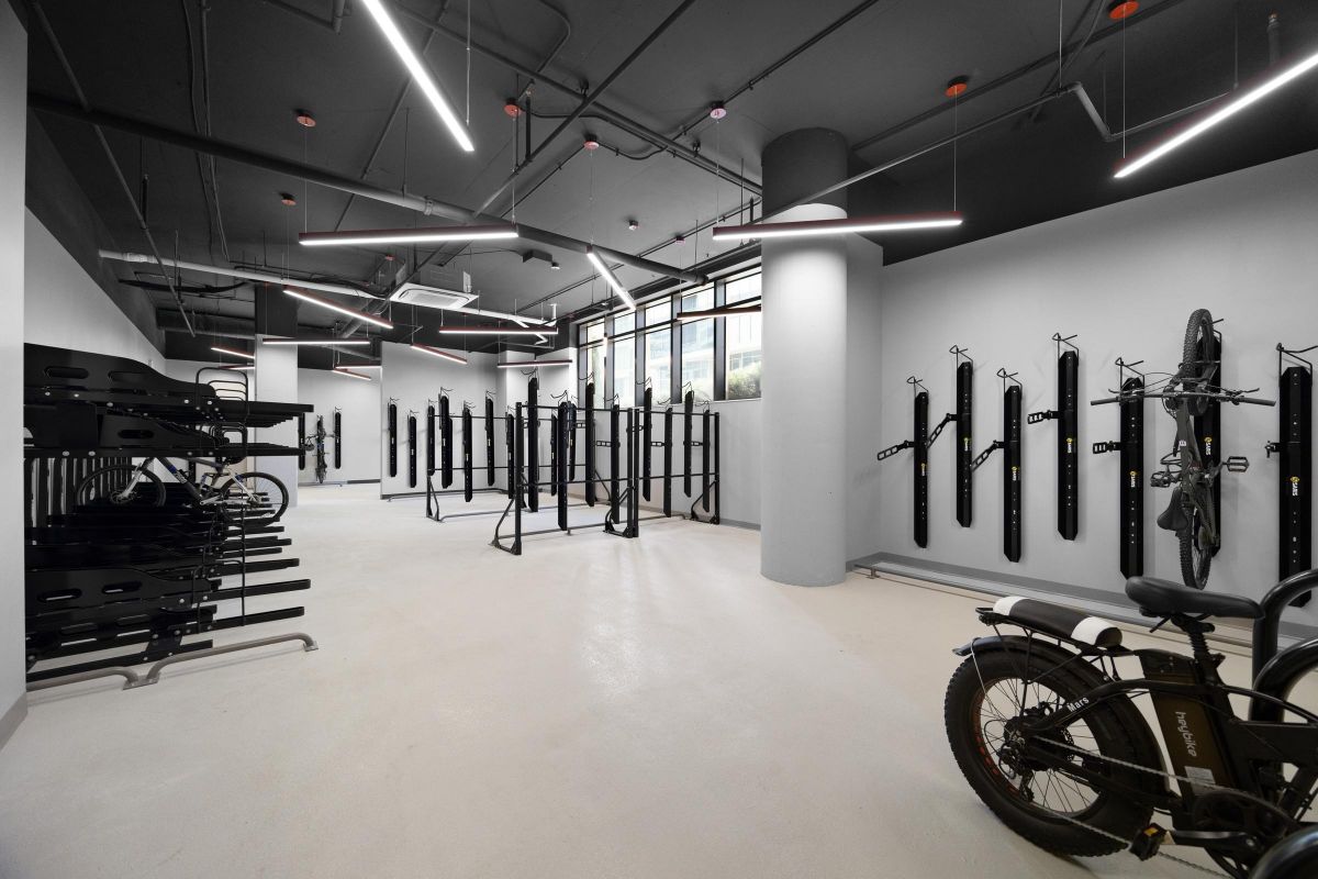 Modern bike storage room with wall-mounted racks, bikes, and sleek lighting.