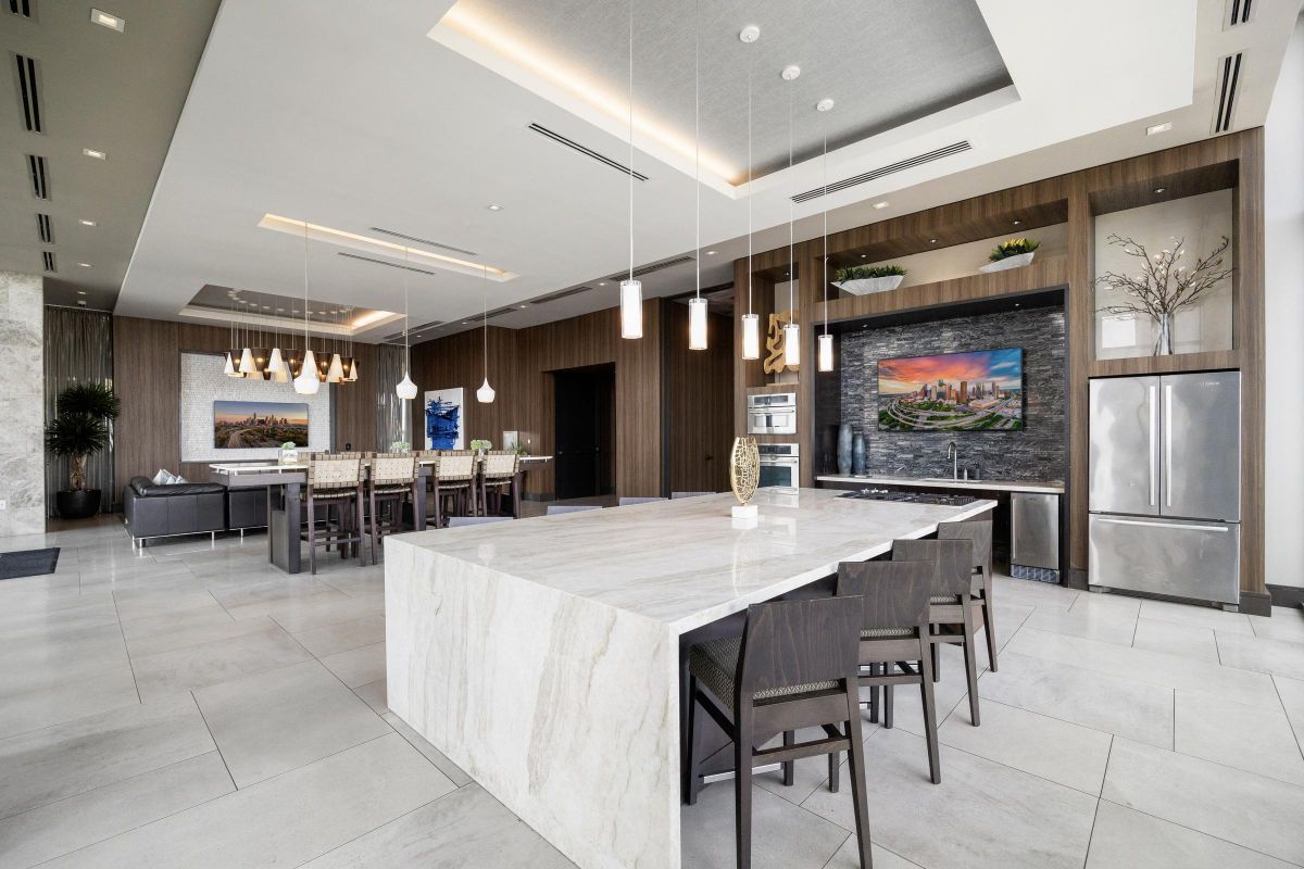 Modern kitchen and dining area with marble island, pendant lights, and contemporary decor.
