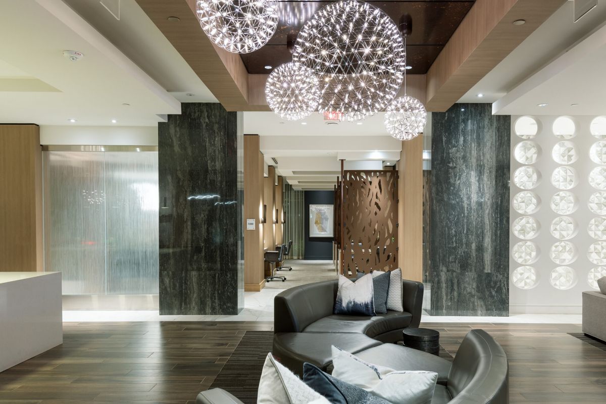 Modern lobby with curved sofas, decorative pillows, and spherical chandelier lights hanging from the ceiling.