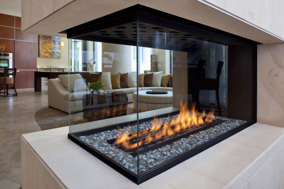 Modern glass-enclosed fireplace with visible flames in a contemporary living room with neutral decor.
